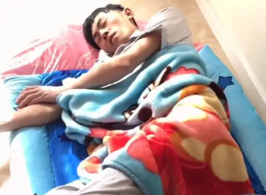 The Four Dogs are lying in bed, looking back at the man sleeping on the couch
